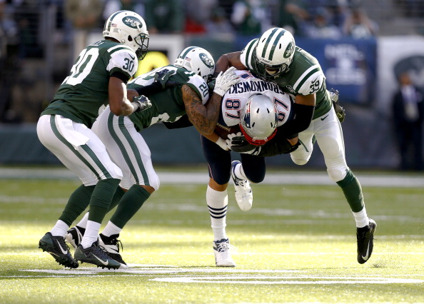 EAST RUTHERFORD, NJ - OCTOBER 20:   Antonio Allen #39, Kyle Wilson #20 and Darrin Walls #30 of the New York Jets take down Rob Gronkowski #87 of the New England Patriots during their game at MetLife Stadium on October 20, 2013 in East Rutherford, New Jersey.  (Photo by Jeff Zelevansky/Getty Images)