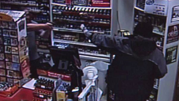 Clerk Shannon Cothran (left) pulls out a gun after a man threatened him with a knife. (Surveillance photo)