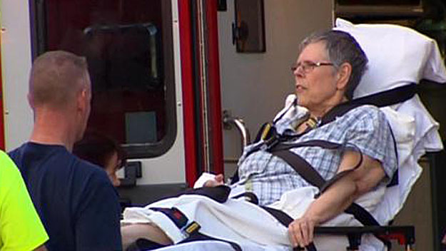 Barabara Kingsbury is placed in an ambulance after the shooting and house explosion in her Brentwood, N.H., neighborhood May 12. (WBZ-TV)