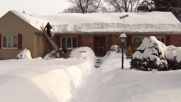 Workers clear snow from a roof (WBZ-TV)