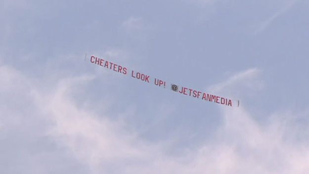 A banner stating "Look up, cheaters!" flies above Gillette Stadium on Thursday, July 30, 2015. (Screen shot from WBZ-TV)