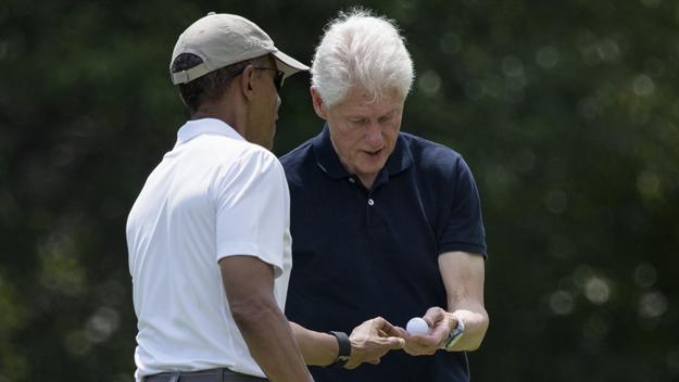 US President Barack Obama (L) hands former US President Bill Clinton a ball after putting while golfing at Farm Neck Golf Club August 15, 2015 in Oak Bluffs, Massachusetts on Martha's Vineyard. (Photo credit should read BRENDAN SMIALOWSKI/AFP/Getty Images)