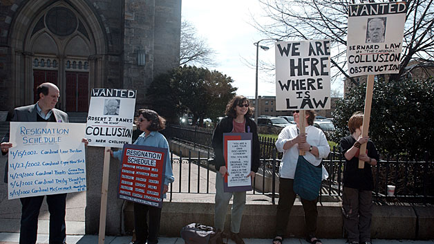 Protestors hold signs calling for the resignation of Cardinal Law outside the Cathedral of the Holy Cross church April 14, 2002. (Photo by Darren McCollester/Getty Images)