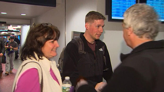 Curtis Leonard, center, welcomed home by his parents Carol and William Leonard at Logan Airport. (WBZ-TV)