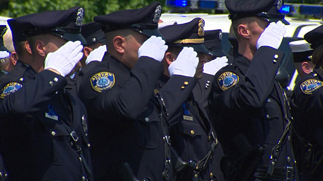 Auburn police officers salute as the casket of Officer Ronald Tarentino arrives in Charlton Thursday. (WBZ-TV)