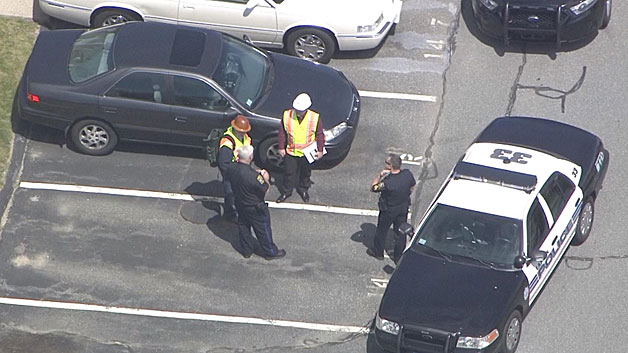Investigators stood next to the manhole in the parking spot after the accident Wednesday. (WBZ-TV)