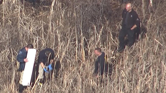 Police remove an item from a wooded area off of Route 128 in Peabody. (WBZ-TV)